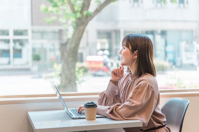 カフェでパソコンを使いながら考える女性