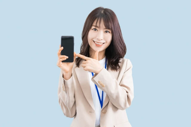 スマホを指差す笑顔のビジネスウーマン