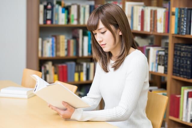 図書館で座って本を読む女子大生