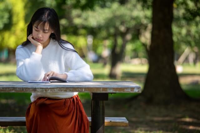 公園のベンチで本を読む女性