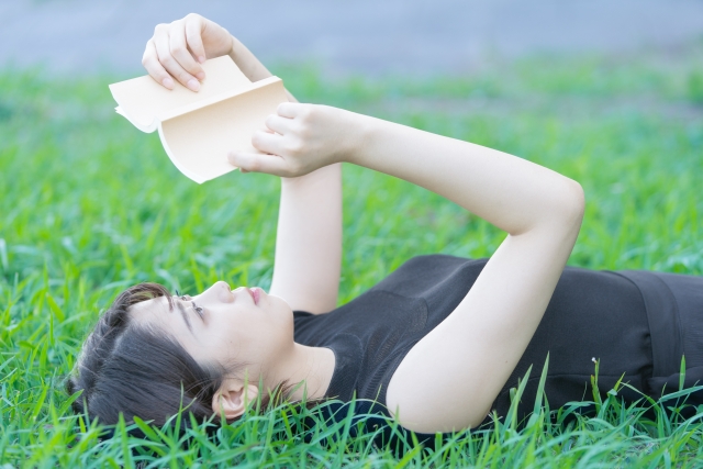 緑地で本を読む女子大生