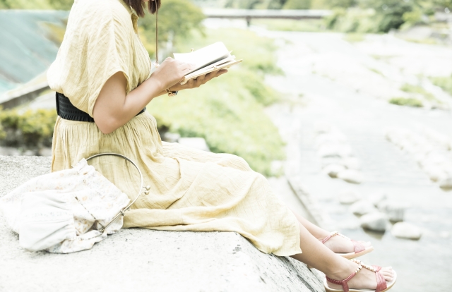 河原で本を読む女性