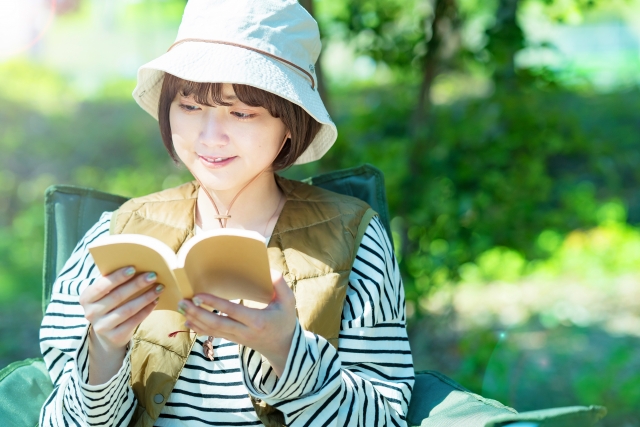 野外で本を読む若い女性