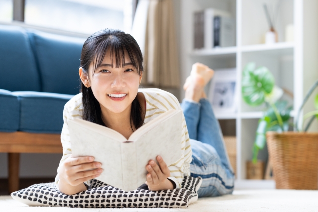 リビングで読書をする若い女性