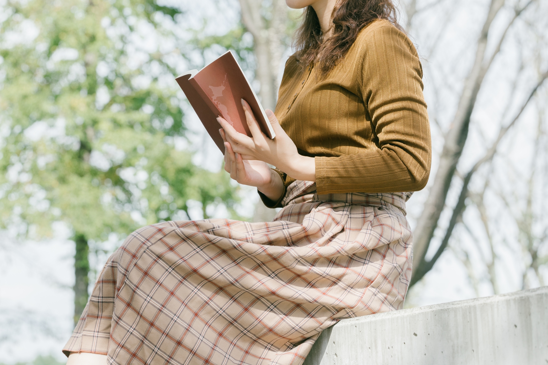 外で読書をする女性　ベンチに座って本を読む人