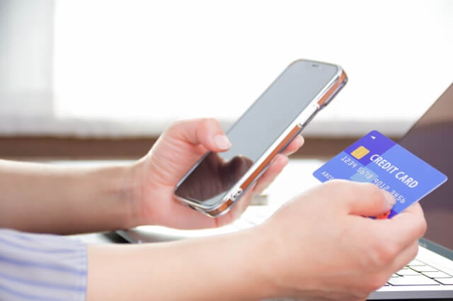 スマートフォンとクレジットカードを持つ女性