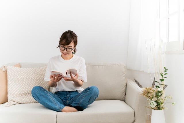 家のソファで読書するおしゃれな日本人女性
