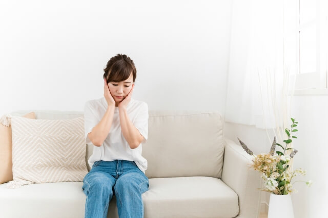 ソファで思い悩む日本人女性（ショック）