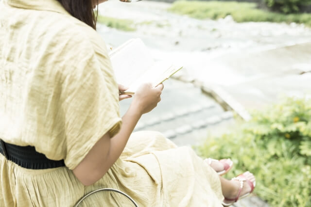 河原で本を読む女性