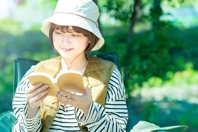 野外で本を読む若い女性