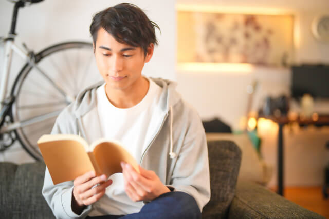 ソファーで読書する男性