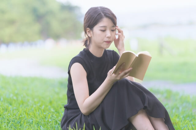 緑地で本を読む女子大生