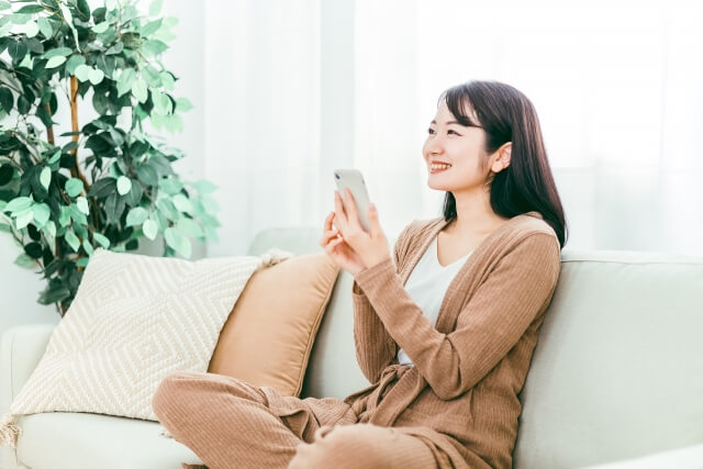 家でスマホを使う笑顔の日本人女性 