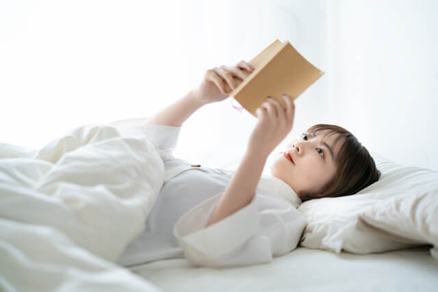 ベッドで本を読む女性