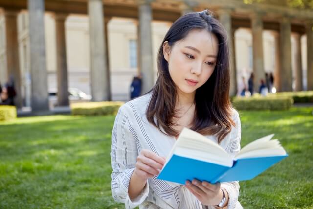 芝生の上で本を読むアジア人女性1
