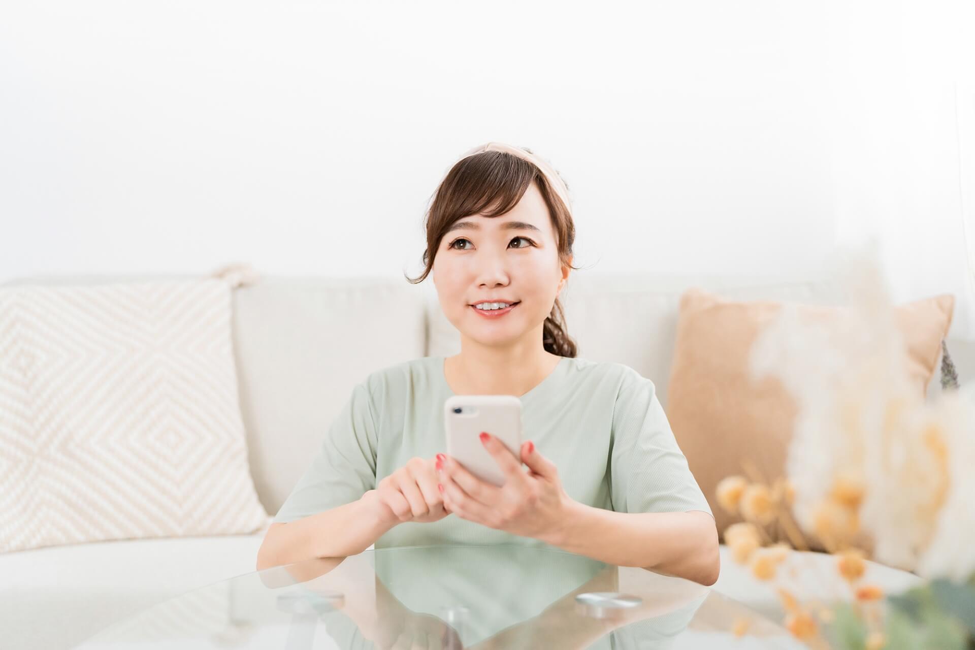 家でスマホを使う笑顔の日本人女性
