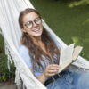 ハンモックで読書中の笑顔女性
