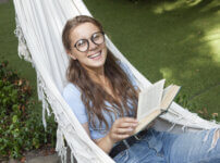 ハンモックで読書中の笑顔女性