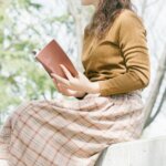 外で読書をする女性　ベンチに座って本を読む人