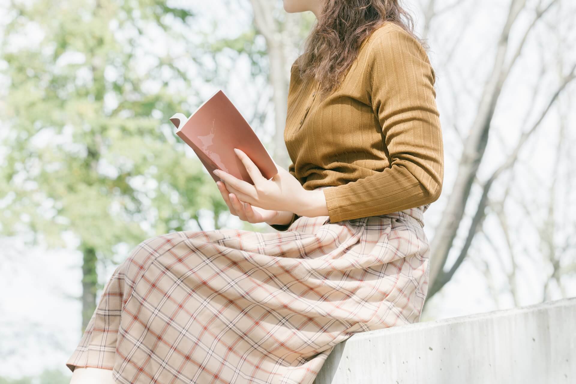 外で読書をする女性　ベンチに座って本を読む人
