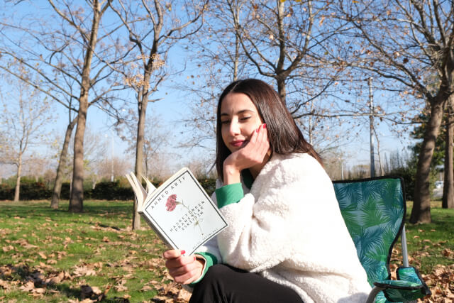秋の公園でアウトドアチェアに座って本を読む女性1