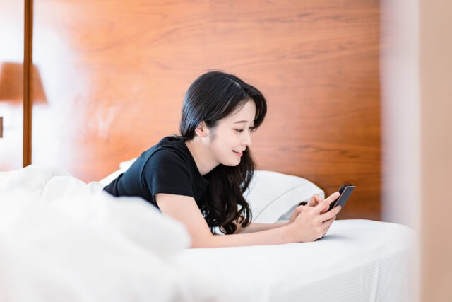 ベッドで電子書籍を読む若い女性