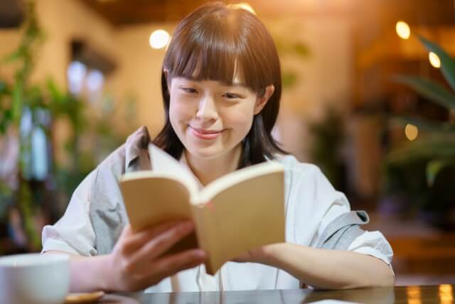 暖かい雰囲気の空間で、本を読む若い女性