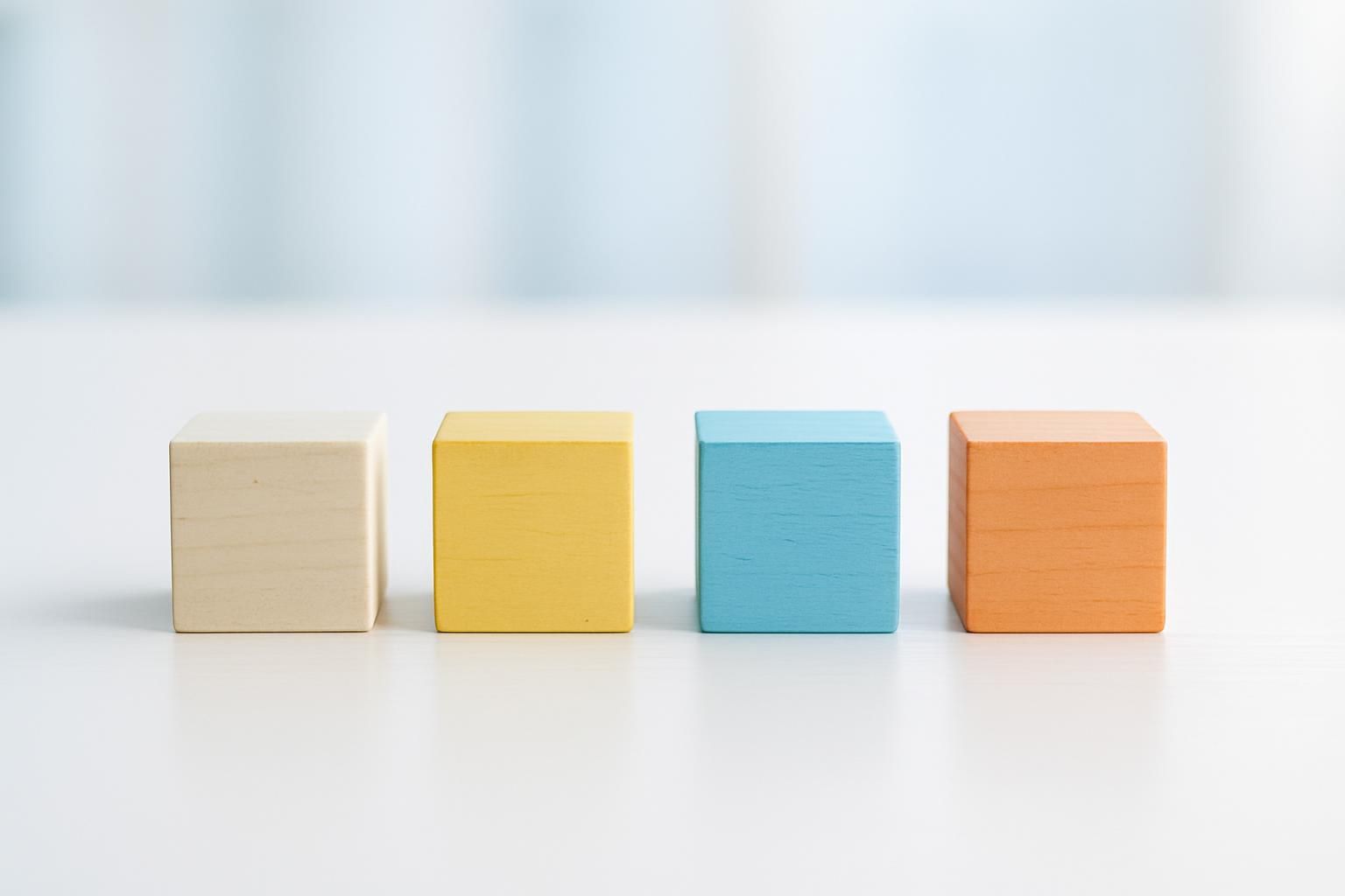白い机の上に等間隔で並んだ4つの色違いの木製ブロック